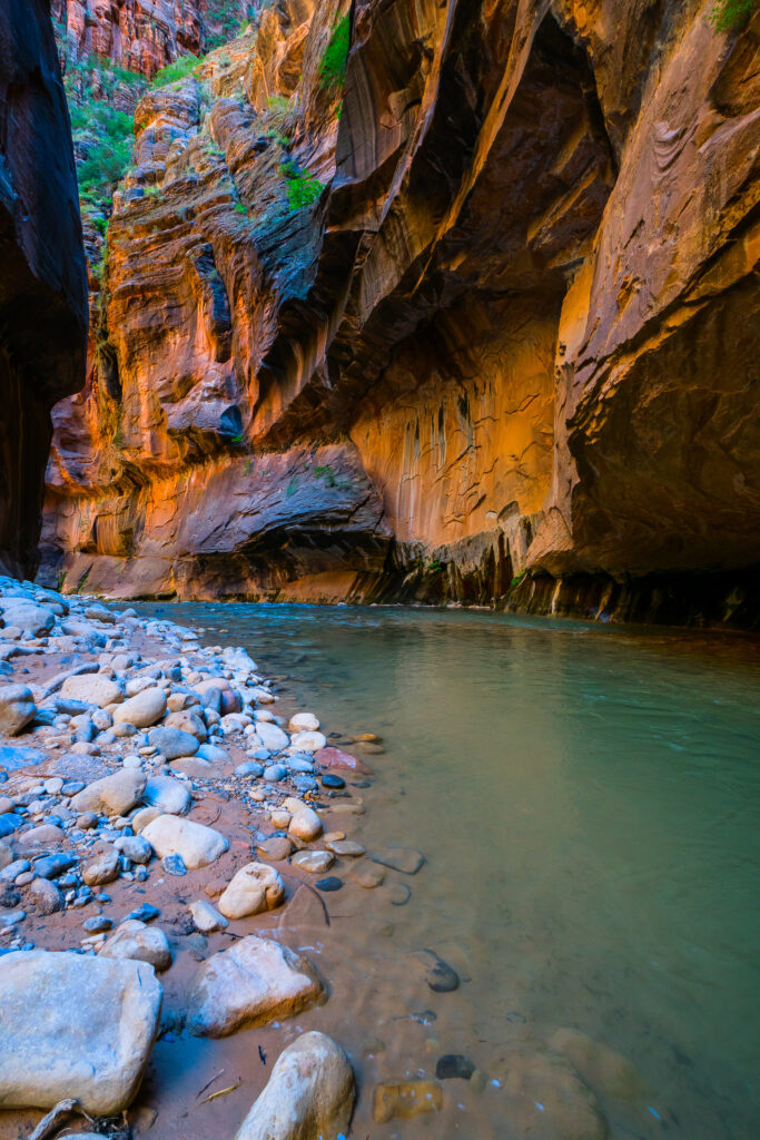 The Narrows canyon in Zion National Park, with turquoise water flowing between towering sandstone walls