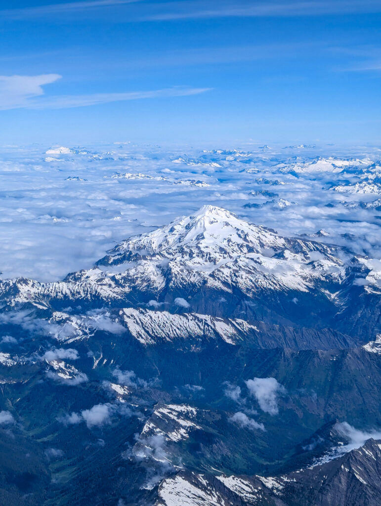 Aerial view of Mount Rainier rising above cloud layer in Washington State during clear daylight conditions