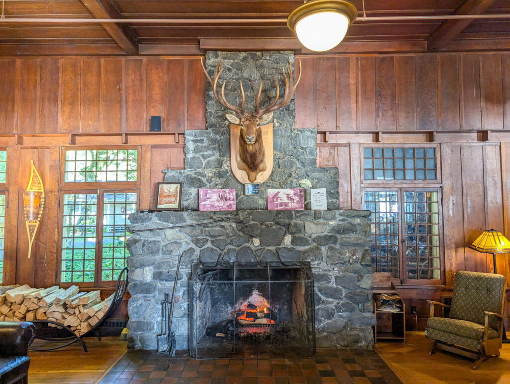 Rustic lodge interior with stone fireplace, mounted deer head, wood-paneled walls, and vintage furniture creating cozy atmosphere at Lake Crescent Lodge, Olympic National Park