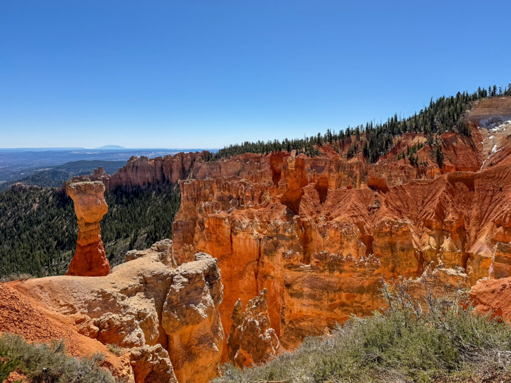 View from Agua Canyon Overlook across a densely packed amphitheater of orange and red hoodoos, with a prominent balanced-rock formation rising on the left.