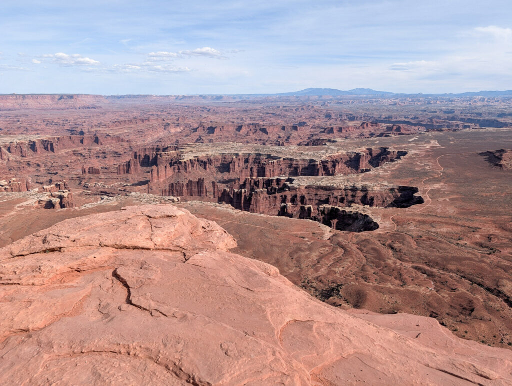 Expansive golden-hour view from Grand View Point over Canyonlands' mesas, canyon walls, and the White Rim far below.