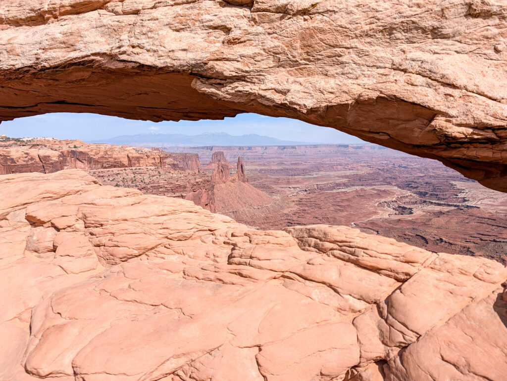 Mesa Arch frames a southeast view across Buck Canyon toward the snow-capped La Sal Mountains in Canyonlands National Park.
