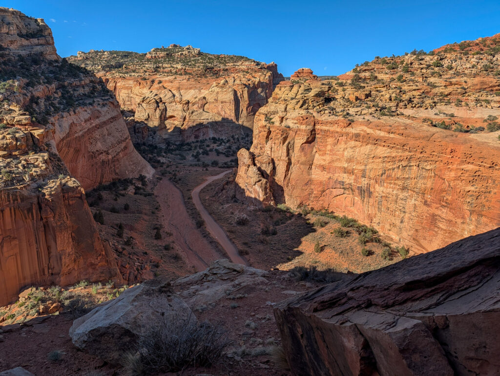 Aerial view of Cohab Canyon Road winding through a narrow red-rock canyon flanked by towering Wingate sandstone walls in Capitol Reef National Park.