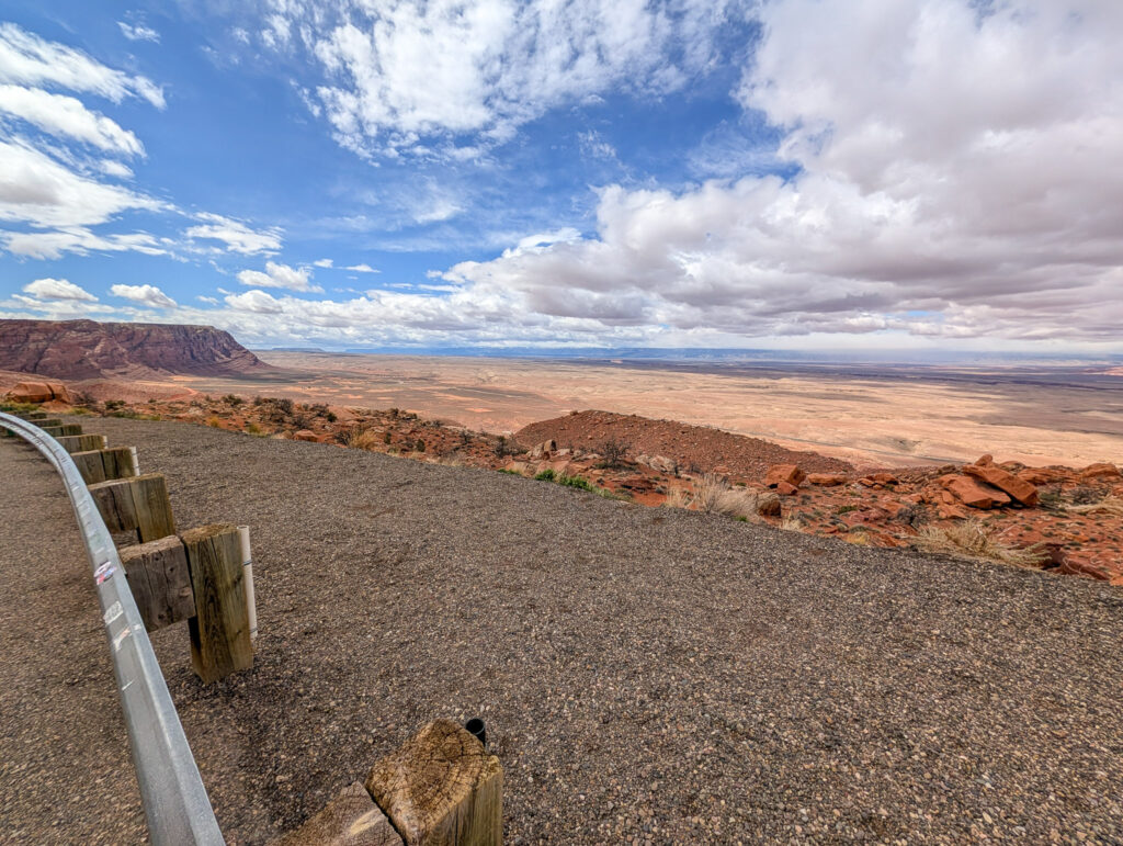 Wide view from Marble Canyon Overlook across House Rock Valley, with Vermilion Cliffs rising to the left under a partly cloudy sky.
