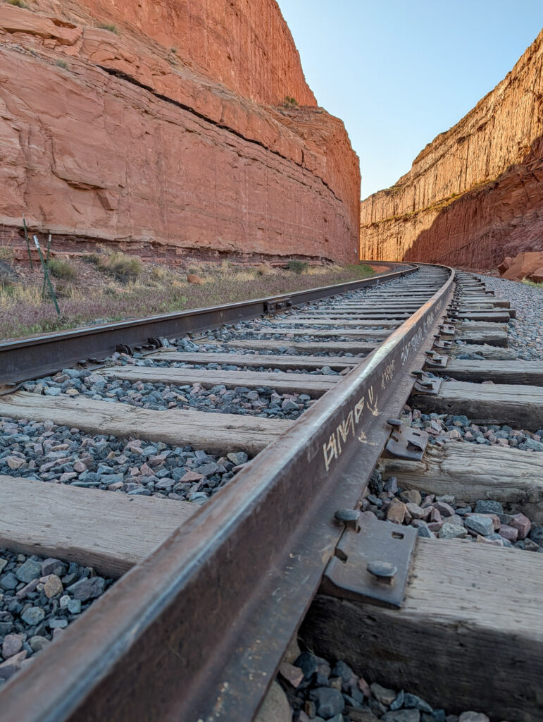 Ground-level view along railroad tracks curving through a narrow red sandstone canyon near Moab, Utah.