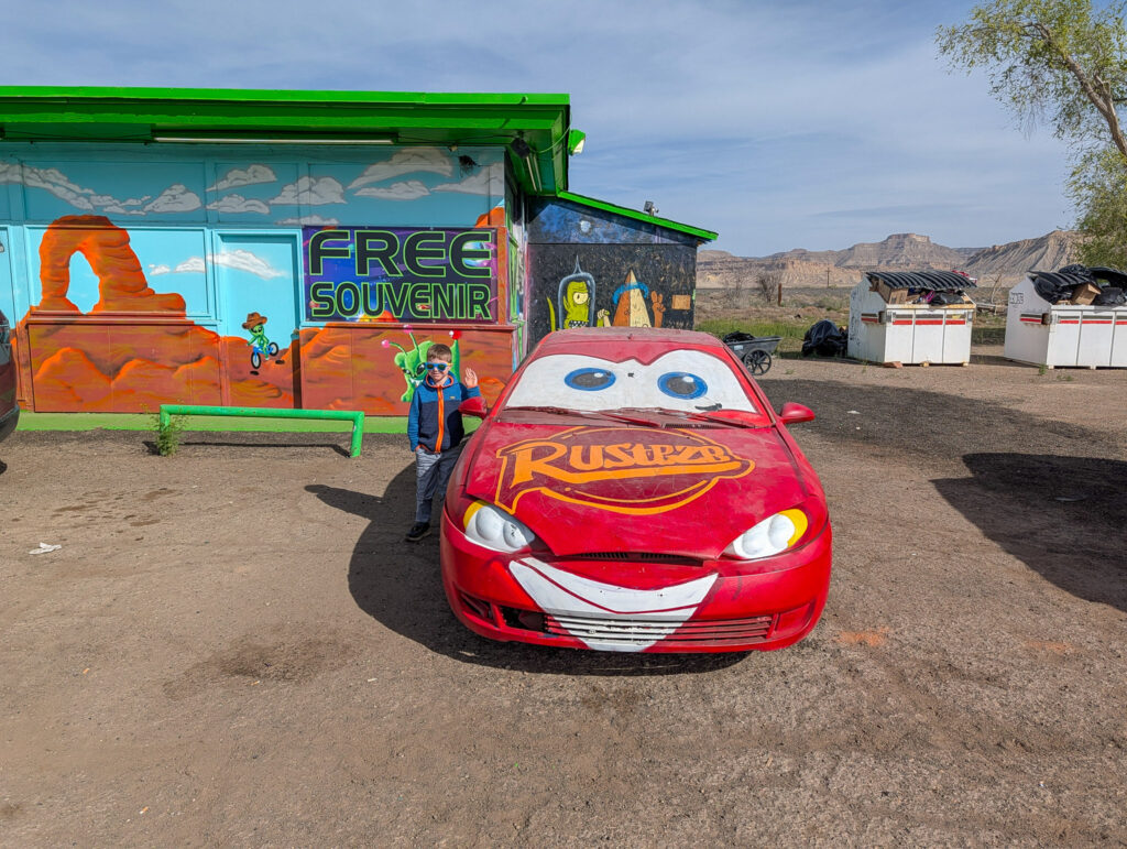 A boy waves beside a car painted as Lightning McQueen outside the Free Souvenir Shop near Moab, Utah.