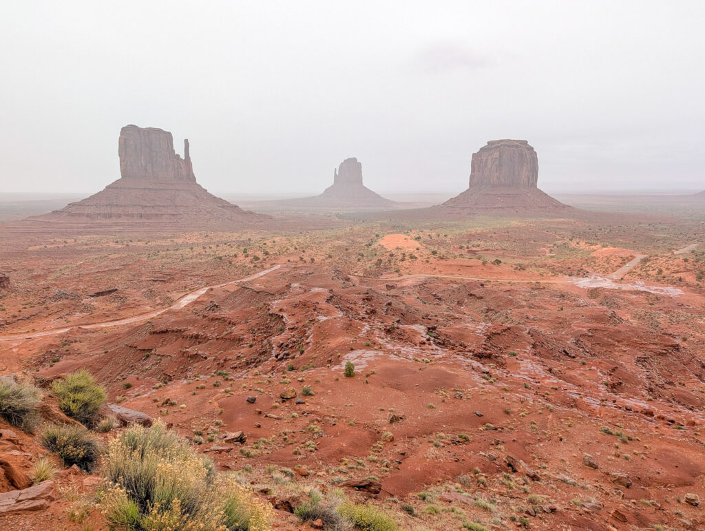 West Mitten, East Mitten, and Merrick Butte rise through fog and low clouds at Monument Valley Navajo Tribal Park.