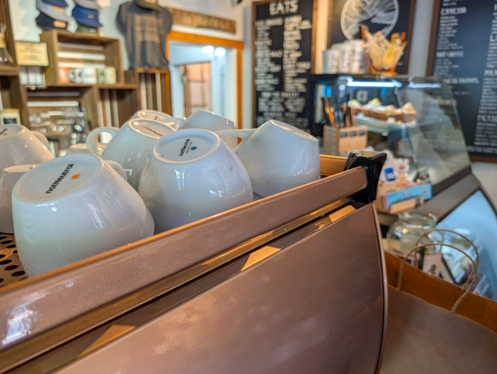 White notNeutral-branded ceramic cups resting upside-down on a mauve espresso machine inside notNeutral café in St. George.