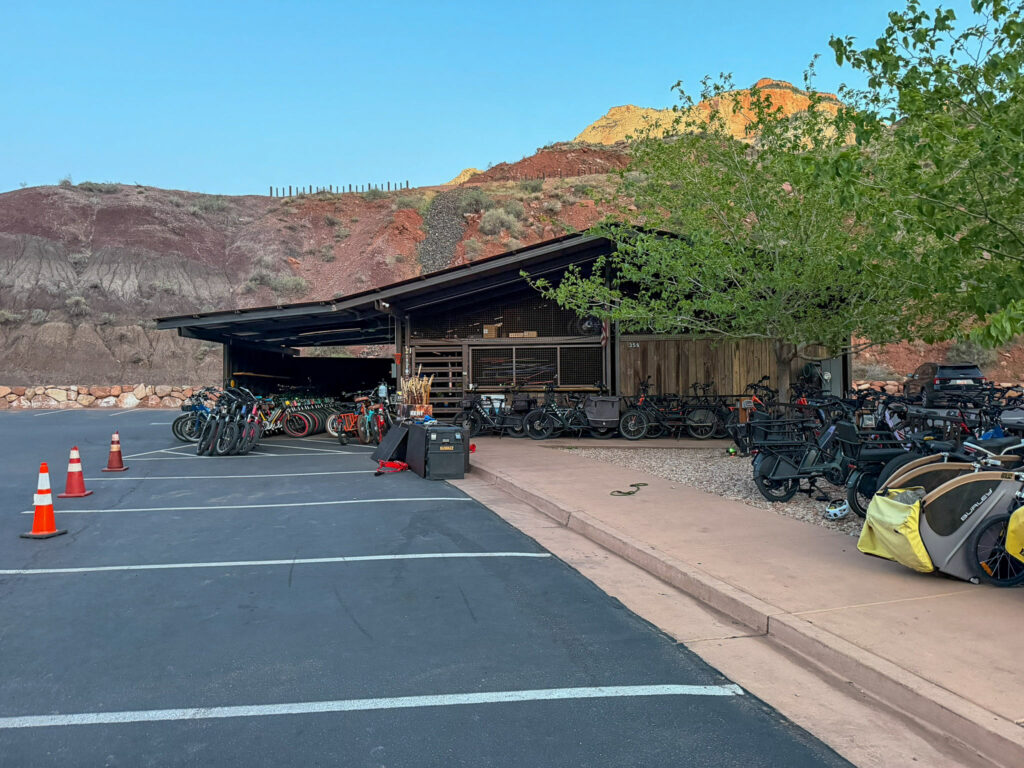 Zion Peddler's ebike rental fleet staged outside their Springdale shop at golden hour, with Zion's red sandstone cliffs glowing in the background.
